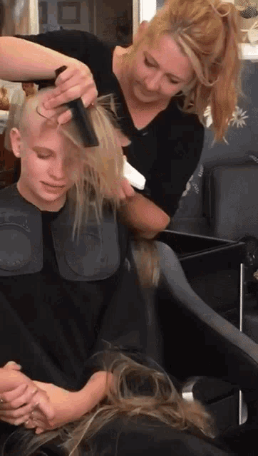 a woman combs a woman 's hair in a salon