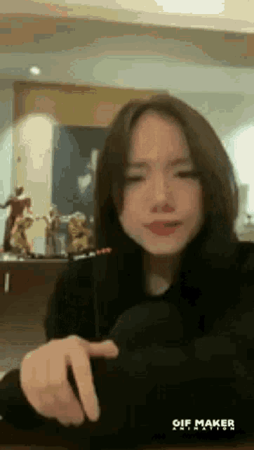 a young woman is sitting at a table with a microphone in her hand and pointing at the camera .