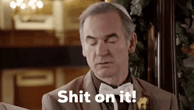 a man in a suit and bow tie is making a funny face and saying shit on it .