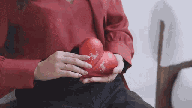 a woman in a red shirt is holding three red balls
