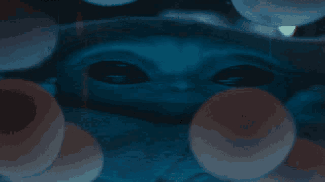 a baby alien is surrounded by balloons and looks at the camera