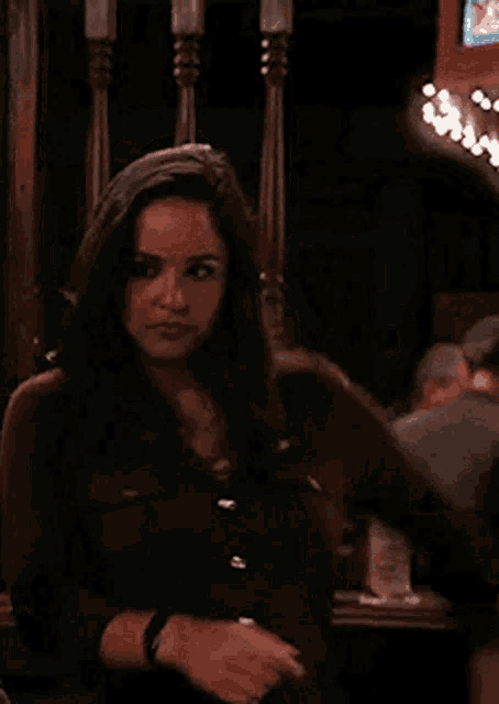 a woman is dancing in a bar while a man holds a cell phone in front of her .
