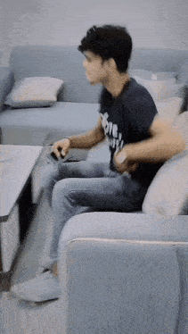 a young man is sitting on a couch holding a cell phone