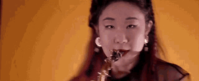 a close up of a woman playing a saxophone in front of a yellow background .