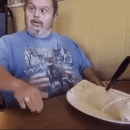 a man with down syndrome is sitting at a table eating food .