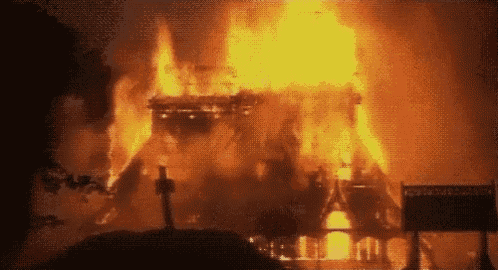 a large fire is burning in a dark room with a sign that says ' ambulance ' on it