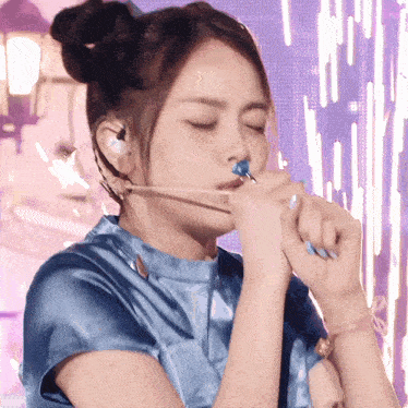 a woman in a blue shirt is blowing bubbles with a blue lollipop