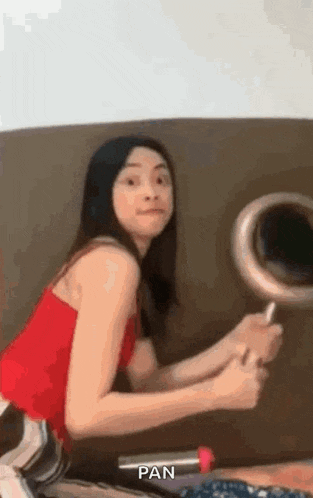 a woman is sitting on a couch holding a mirror .