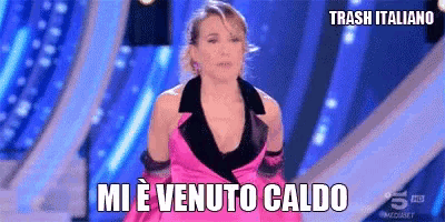a woman in a pink dress stands on a stage with the words mi e venuto caldo above her