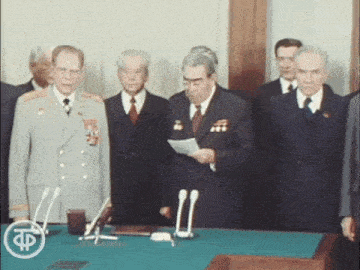 a group of men standing around a table with a tp logo