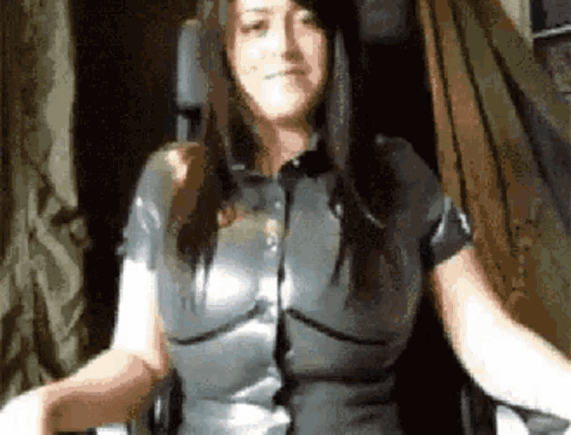 a woman is sitting in a chair with her arms outstretched and wearing a latex suit .