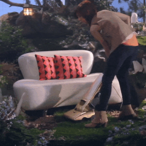 a woman is using a vacuum cleaner to clean a couch in a garden