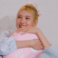 a woman is holding a pink pillow in her arms and laughing .