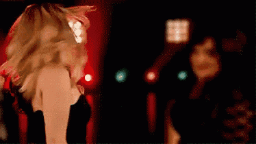 a woman is dancing in a dark room with red lights .