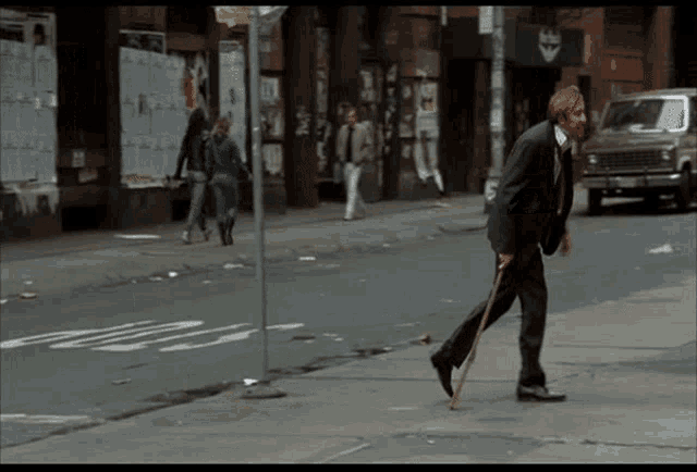 a man with a cane walks down a street in front of a building that says ' king '