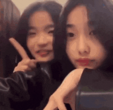 a couple of girls are taking a selfie together and making a peace sign .