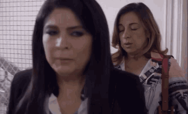 two women are standing next to each other in a room with their eyes closed .