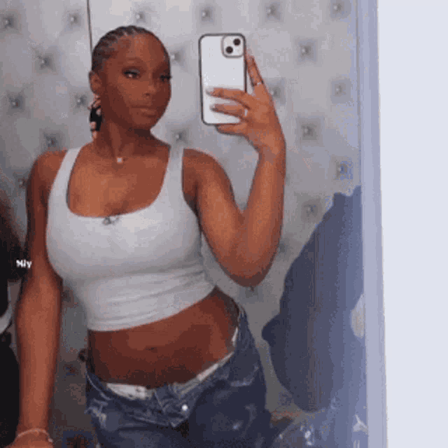 a woman is taking a picture of herself in a mirror with her phone .