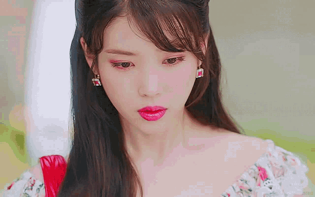 a close up of a woman 's face wearing a floral dress and earrings
