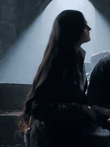 a woman with long hair is standing in the dark
