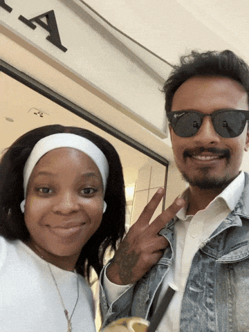a man and a woman pose for a picture in front of a sign that says a