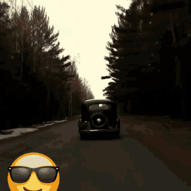 a car is driving down a road next to a smiley face with sunglasses