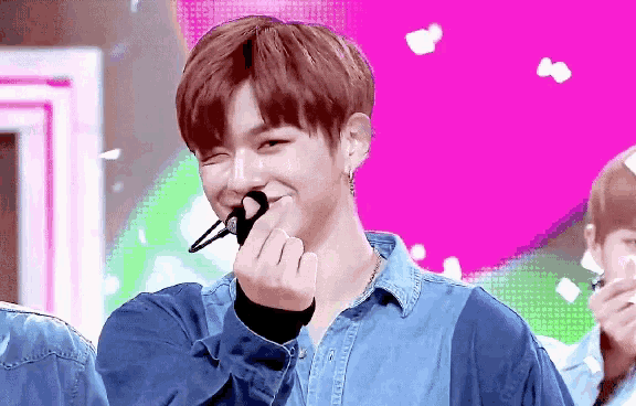 a young man in a blue shirt is making a heart shape with his hands