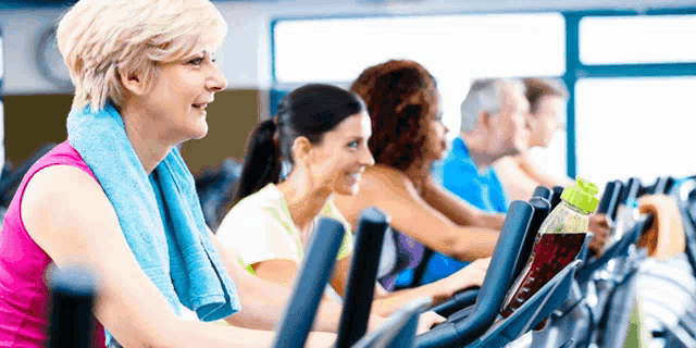 a woman with a blue towel around her neck is riding an exercise bike in a gym