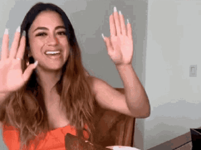 a woman is sitting at a table waving her hands in the air .
