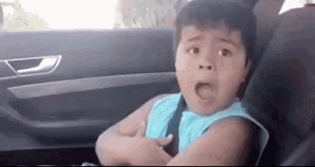 a young boy is sitting in the back seat of a car with his arms crossed .