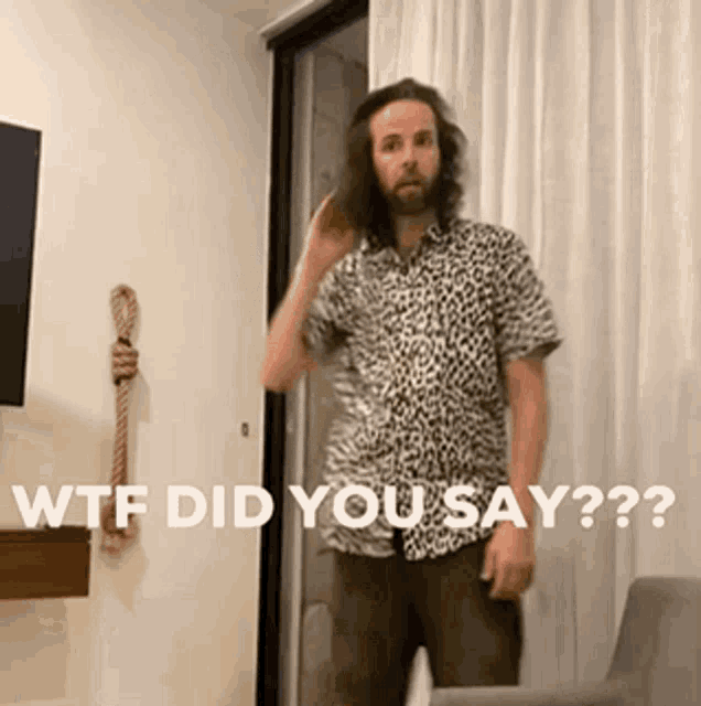 a man in a leopard print shirt is standing in front of a door and says wtf did you say