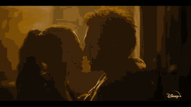 a man and a woman are kissing in front of a window .