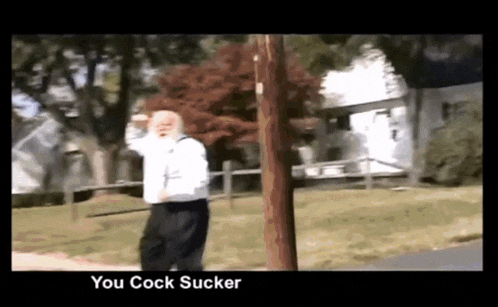 a man standing next to a pole with the words you cock sucker on the bottom right