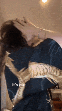 a woman covering her face with her hands with the words it 's out visible