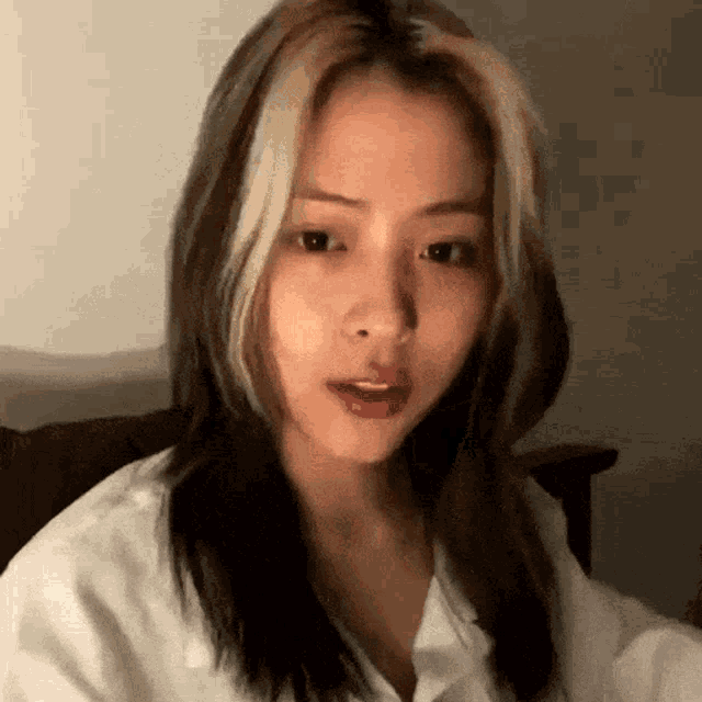 a close up of a woman 's face with long hair and a white shirt