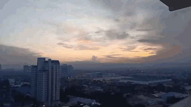 an aerial view of a city at sunset with a cloudy sky