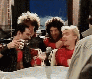 a group of men are sitting around a table with a microphone and drinking .