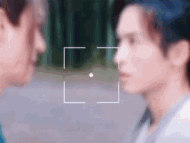 a blurry photo of two men looking at each other with a white square in the middle