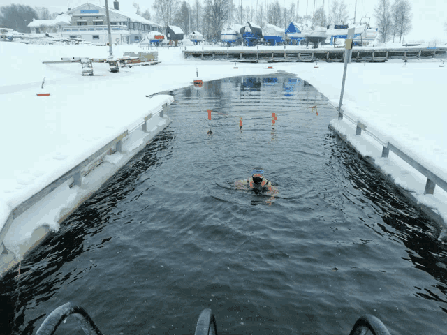 a person is swimming in a body of water in the winter
