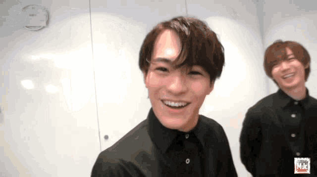 a man with braces on his teeth is smiling while standing next to another man