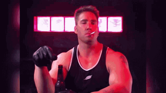 a man in a black tank top is smoking a cigarette and holding a beer bottle .