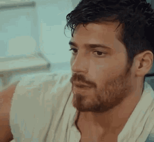 a close up of a man with a beard wearing a white shirt and a towel around his neck .