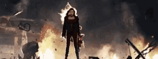 a woman in a red dress is standing in front of a huge explosion .