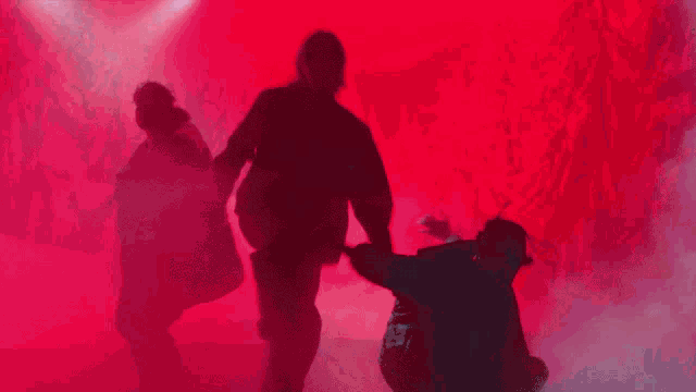 a group of people are standing in a foggy room and one of them is laying on the ground