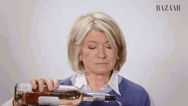 a woman is pouring a bottle of wine from a glass .