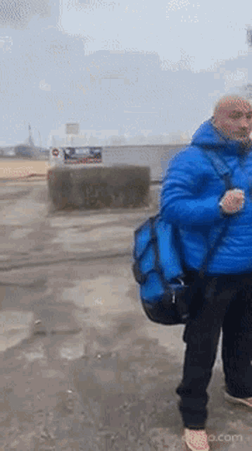 a man in a blue jacket with a blue bag on his shoulder