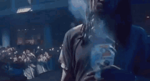 a man is smoking a cigarette on stage in front of a crowd of people .