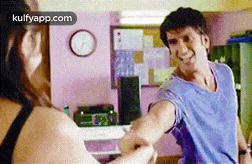 a man is holding a woman 's hand in a room .