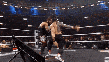 two wrestlers are fighting in a ring with a crowd watching