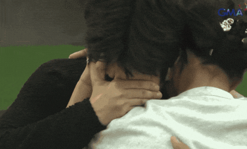 a woman covering a man 's face with her hands with gma written on the bottom
